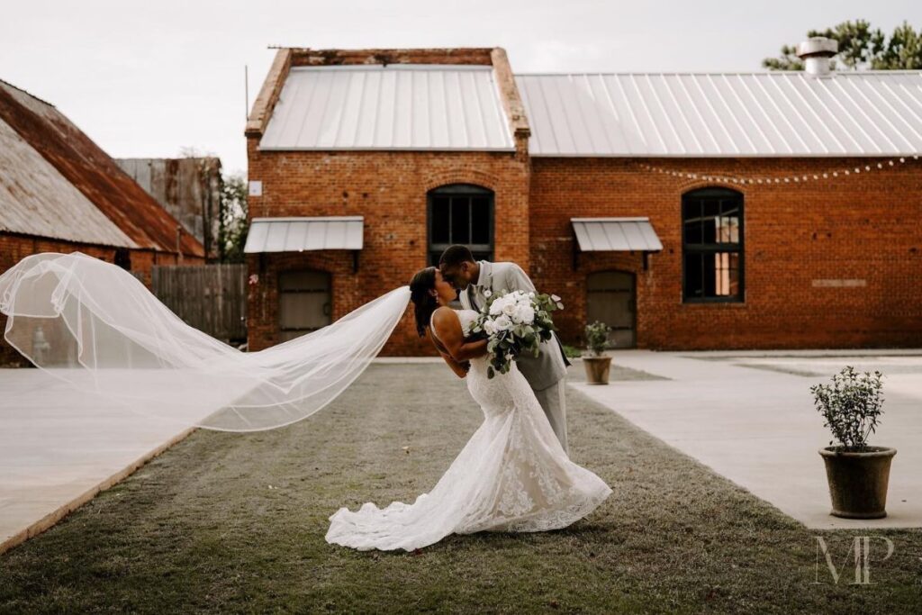 Newly married couple kiss at Empire Mills' courtyard.
