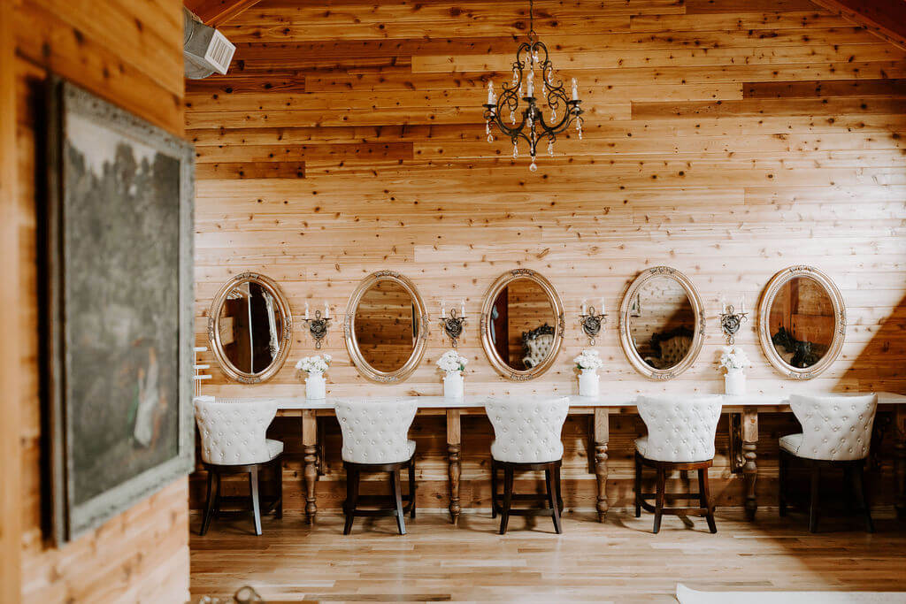 Photo of dressing room in The Dogwood Barn with 5 seats and mirrors and a chandelier above
